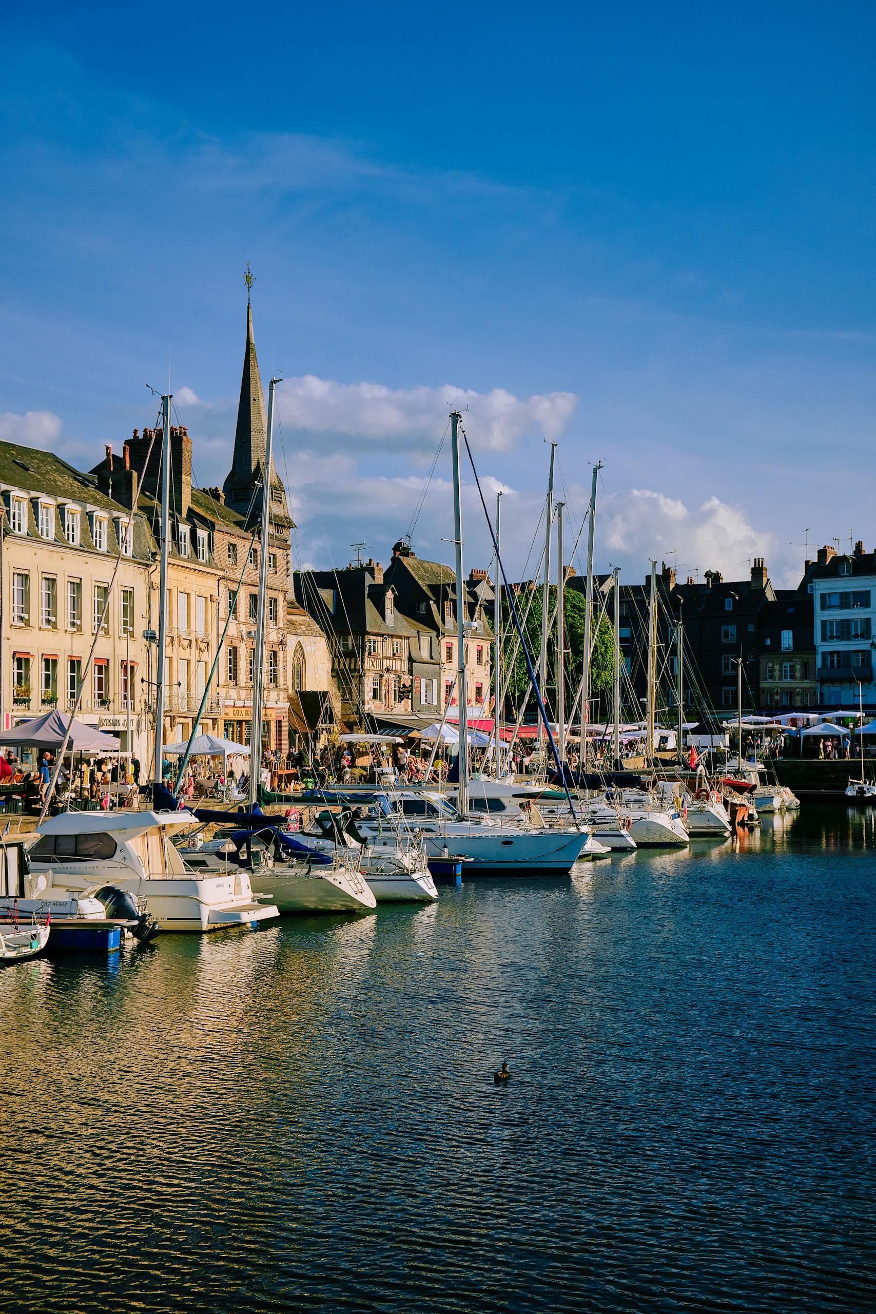 Scenic view of Honfleur Marina, Normandy with yachts and historic architecture at sunset.